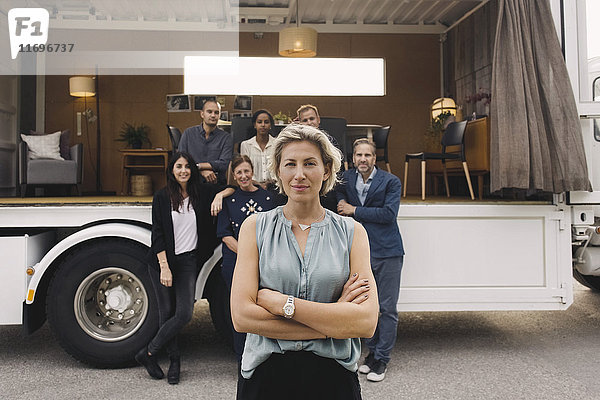 Porträt einer selbstbewussten Geschäftsfrau mit Team und tragbarem Bürotruck im Hintergrund