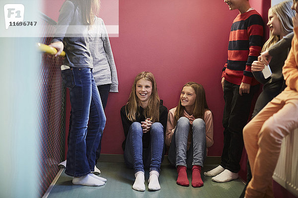 Lächelnde Mädchen mit männlichen und weiblichen Freunden in der Mittelschule