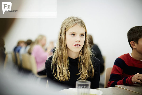 Nachdenkliches Mädchen am Tisch während der Mittagspause in der Schulcafeteria