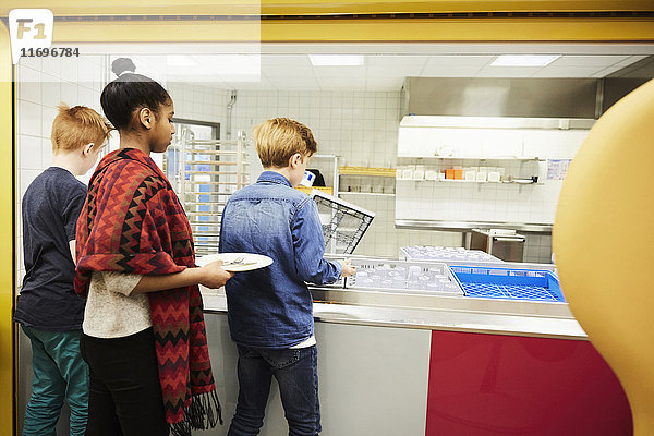 Schüler legen nach dem Mittagessen in der Schulcafeteria Teller in die Kiste