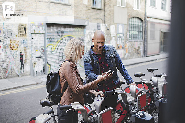 Paar mit Mobiltelefonen am Fahrrad-Sharing-System