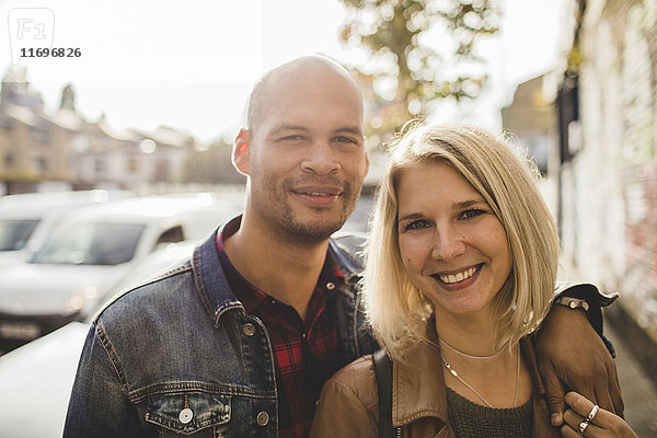 Porträt eines liebenden Paares  das auf dem Bürgersteig in der Stadt lächelt.