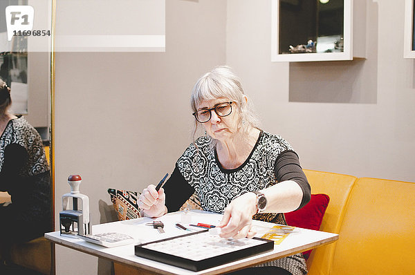 Senior Schmuckmacherin am Schreibtisch in der Werkstatt