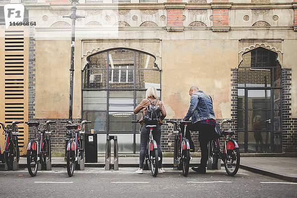 Durchgehende Rückansicht des Fahrradverleihpaares vom Fahrradständer in der Stadt