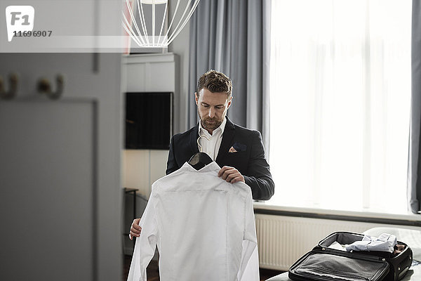 Geschäftsmann mit weißem Hemd im Kleiderbügel am Fenster im Hotelzimmer