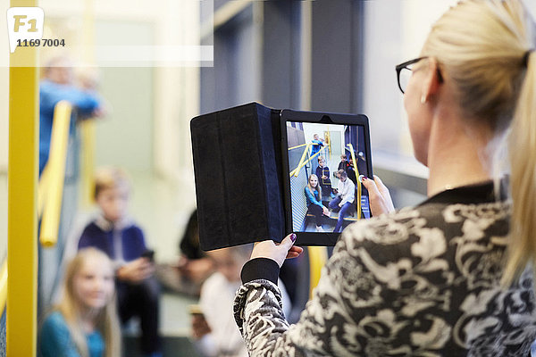 Lehrer fotografiert Schüler durch digitales Tablett in der Schule