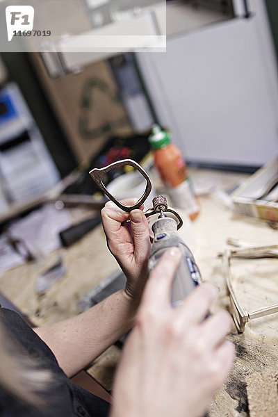 Abgeschnittenes Bild der Brillenmacherin mit Arbeitsgerät in der Werkstatt