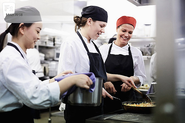 Lehrerin beobachtet Kochschülerinnen beim Kochen in der Großküche