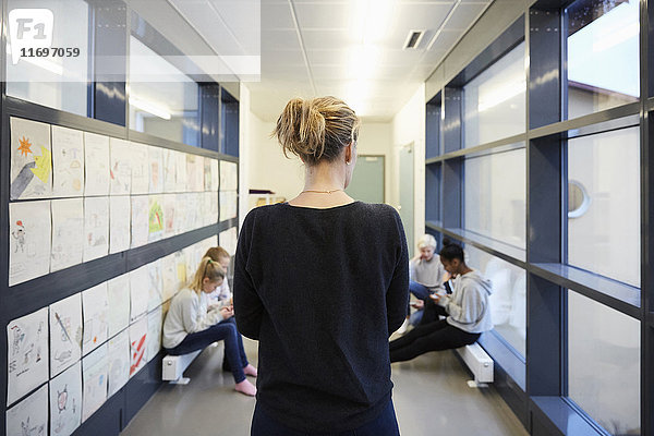 Rückansicht des Lehrers mit Blick auf die Schüler im Schulflur