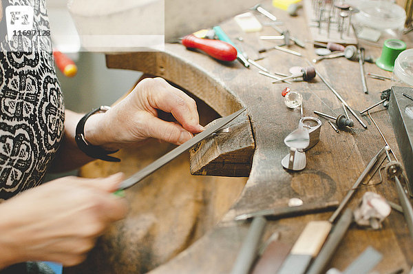 Abgeschnittenes Bild eines älteren Handwerkers  der in der Werkstatt Schmuck herstellt.