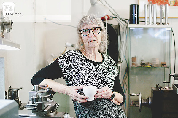 Porträt einer selbstbewussten Seniorin mit Kaffeetasse im Juweliergeschäft