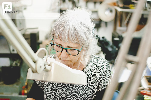 Seniorin mit Brille bei der Arbeit in der Schmuckwerkstatt