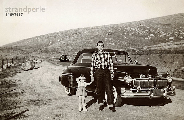 Porträt von kaukasischem Vater und Tochter  die in der Nähe eines Oldtimers posieren