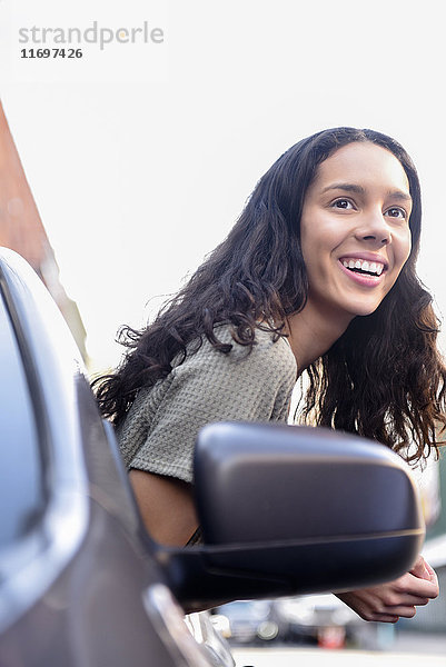 Hispanische Frau lehnt sich aus dem Autofenster