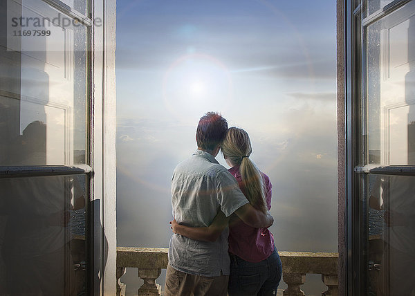 Kaukasisches Paar bewundert malerische Aussicht auf den See vom Balkon aus