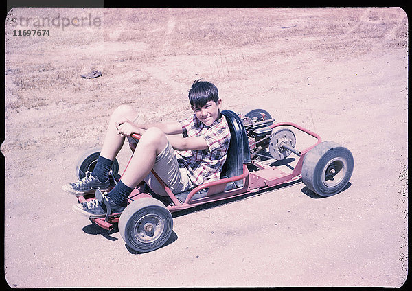 Porträt eines kaukasischen Jungen  der auf einem Go-Kart sitzt