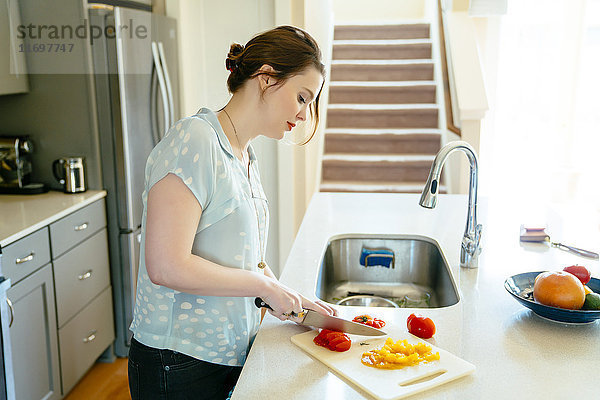 Frau schneidet Lebensmittel in der häuslichen Küche