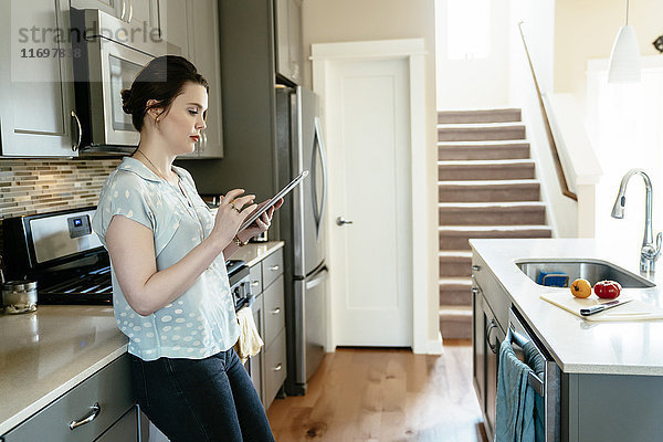 Frau benutzt digitales Tablet in der heimischen Küche