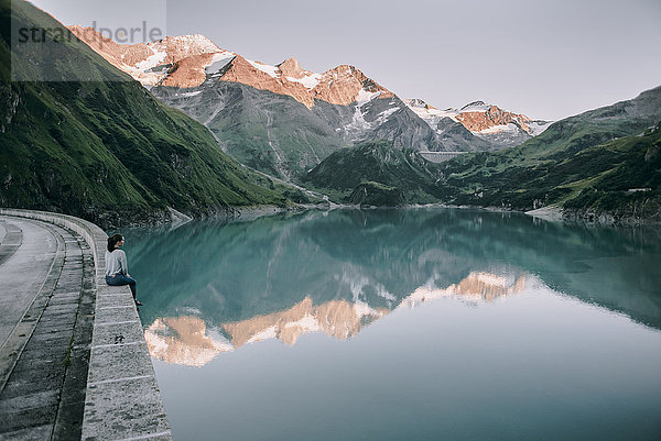 Kaukasische Frau sitzt auf einer Mauer am Bergsee