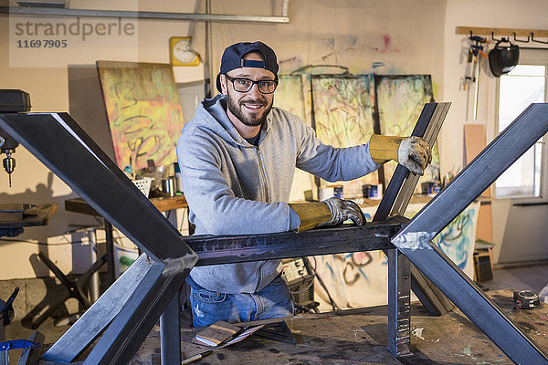 Porträt eines kaukasischen Mannes  der sich auf eine Metallskulptur stützt