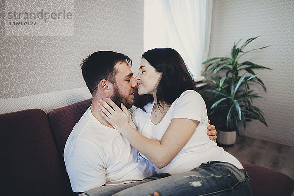 Kaukasisches Paar kuschelnd und küssend auf Sofa