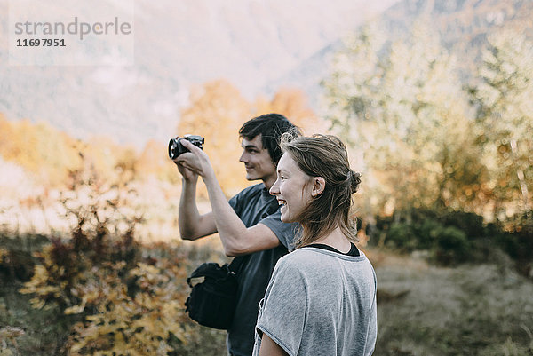 Kaukasisches Paar beim Fotografieren mit Kamera im Herbst