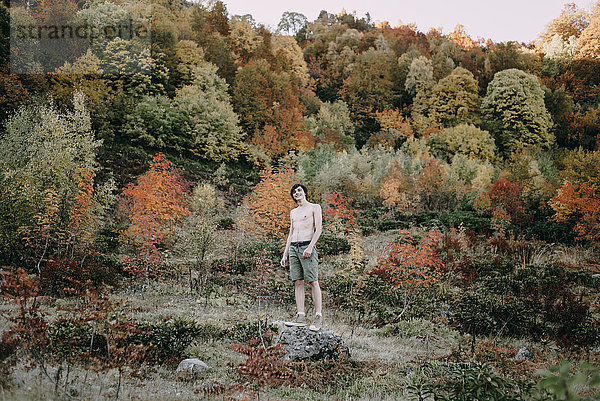 Kaukasischer Mann steht im Herbst auf einem Felsen