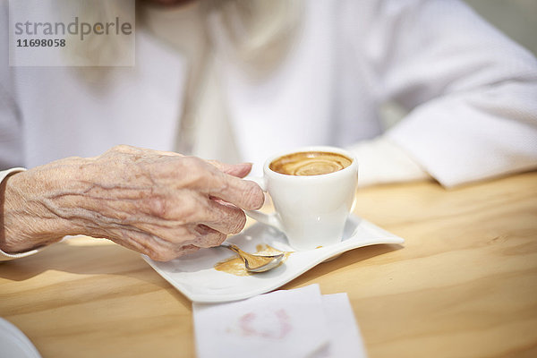 Hand einer älteren kaukasischen Frau beim Kaffeetrinken