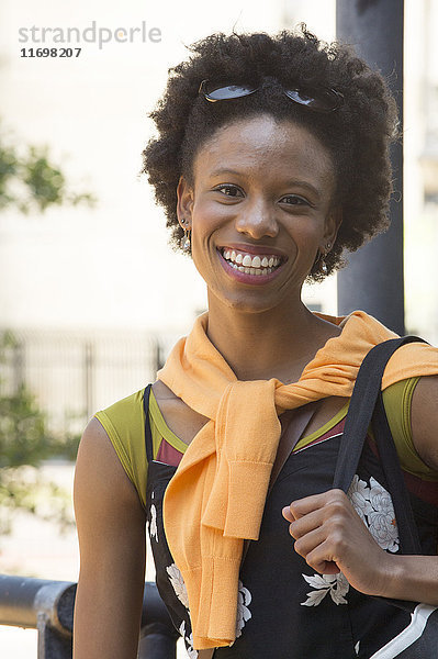Porträt einer lächelnden afroamerikanischen Frau mit Handtasche