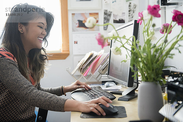 Gemischtrassige Frau sitzt am Schreibtisch und benutzt einen Computer