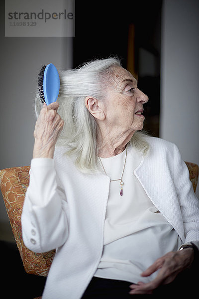 Ältere kaukasische Frau beim Bürsten der Haare