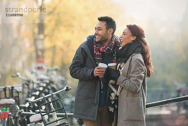 Lächelndes junges Paar in warmer Kleidung trinkt Kaffee in der Stadt