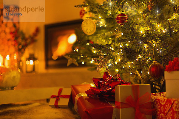 Geschenke unter dem Weihnachtsbaum im stimmungsvollen Wohnzimmer mit Kamin