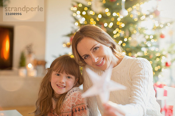 Portrait lächelnde Mutter und Tochter mit Weihnachtsstern