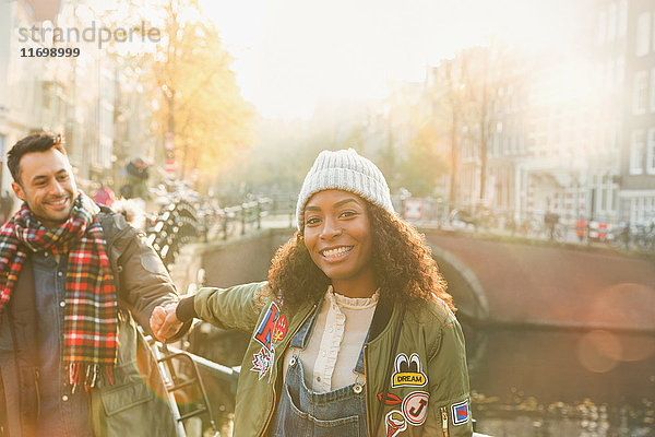 Porträt eines lächelnden jungen Paares am Kanal in Amsterdam