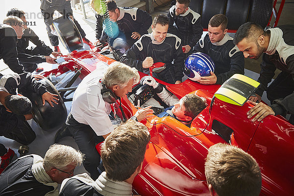 Manager und Boxencrew rund um Formel 1 Fahrer im Rennwagen