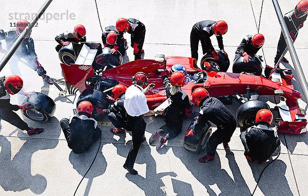 Manager mit Stoppuhr-Timing-Pit-Crew beim Reifenwechsel an Formel 1-Rennwagen in der Boxengasse