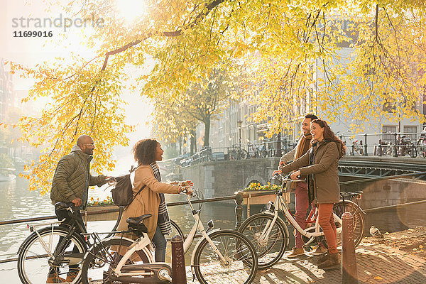 Freunde mit Fahrrädern am sonnigen Herbstkanal in Amsterdam