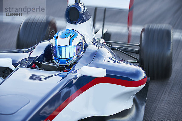 Formel-1-Rennwagenfahrer im Helm auf der Sportstrecke