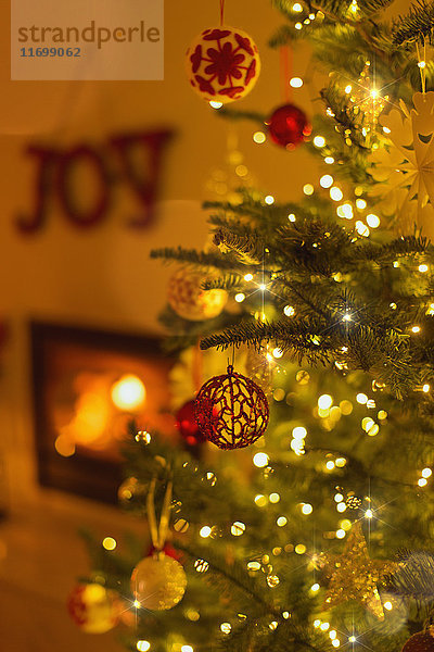 Weihnachtsschmuck am Weihnachtsbaum mit Lichterkette im Wohnzimmer