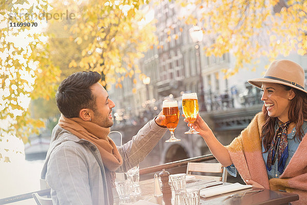 Junges Paar rösten Biergläser im städtischen Herbstcafé  Amsterdam