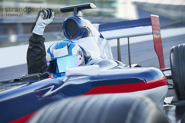 Portrait Formel 1 Rennfahrer mit Helm und Jubel mit der Faust auf der Sportstrecke