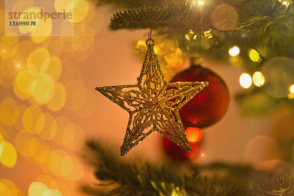 Close up Gold Star Ornament hängen von Weihnachtsbaum Zweig