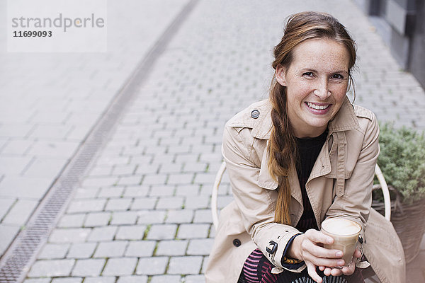 Portrait lächelnde Frau trinkt Eiskaffee in einem Straßencafé