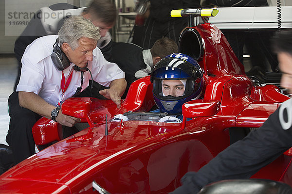 Manager im Gespräch mit Formel-1-Rennfahrer in der Werkstatt