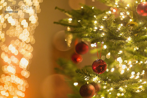 Rote Ornamente hängen am Weihnachtsbaum mit Lichterkette