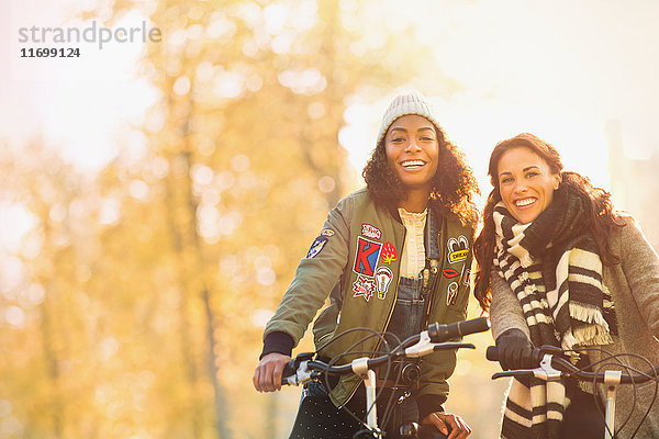 Portrait lächelnde junge Frauen Freunde Radfahren auf der Herbststraße