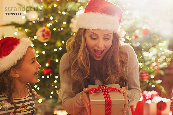 Überrumpelte Mutter mit Weihnachtsmannmütze erhält Weihnachtsgeschenk von Tochter