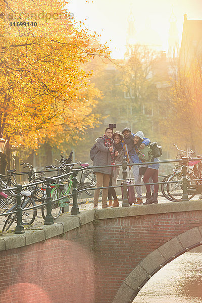 Freunde nehmen Selfie mit Selfie-Stick auf der Herbstbrücke über den Kanal in Amsterdam
