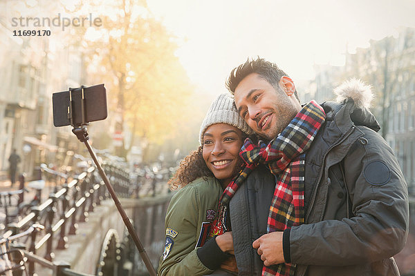 Zärtliche Paarumarmung und Selfie mit Selfie-Stick auf der Herbstbrücke  Amsterdam